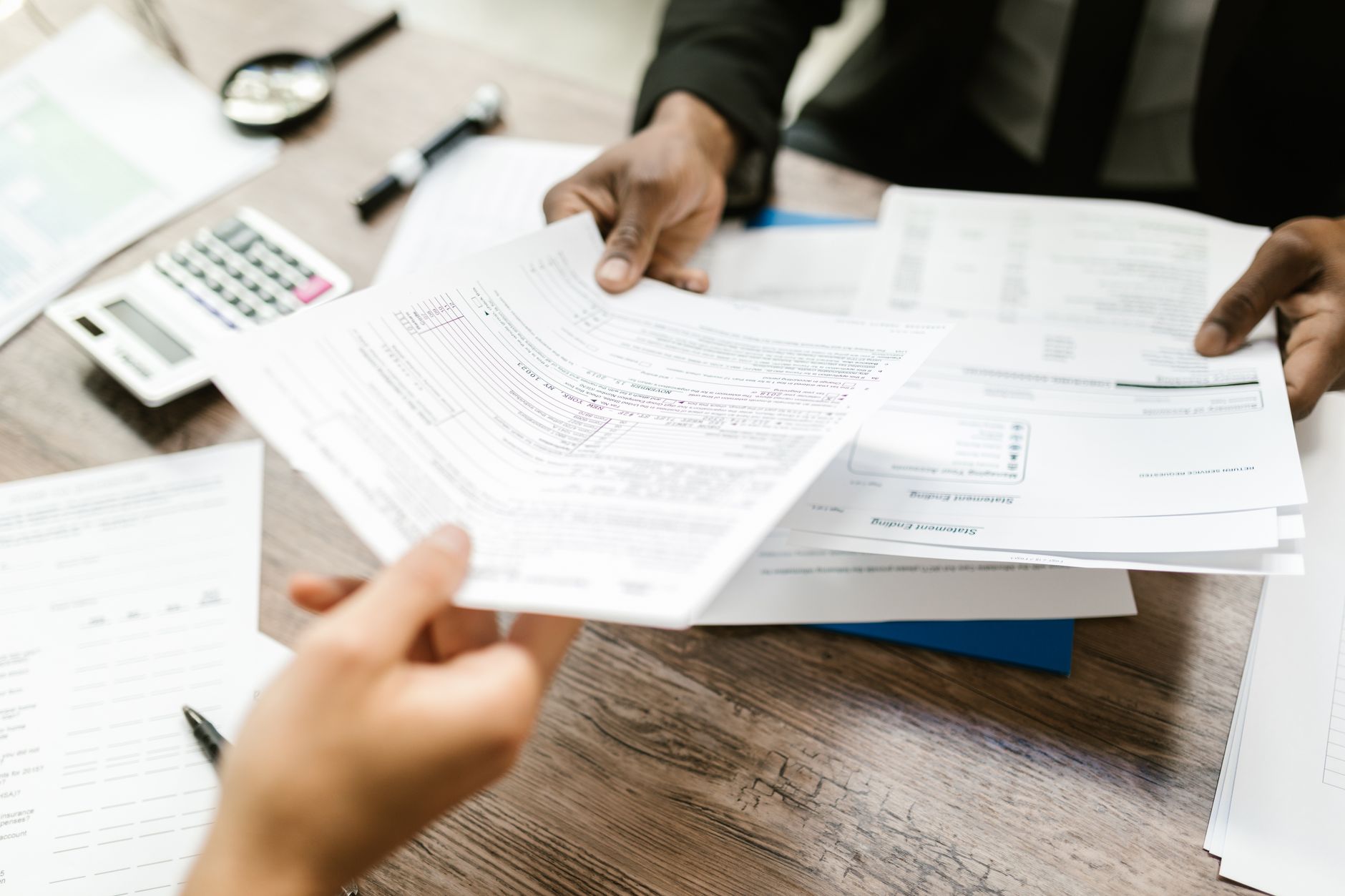 A founder handing financial documents to a non-dilutive lender during underwriting