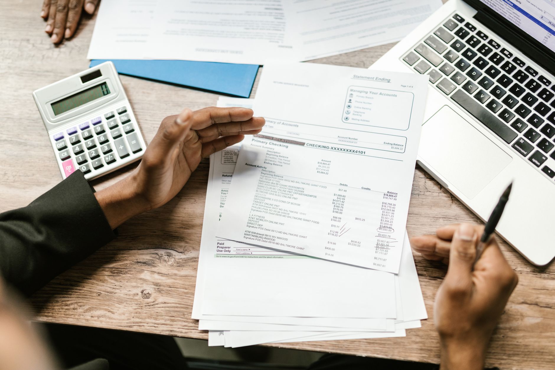 Hands reviewing a financial statement with a calculator to tally the fees on a debt facility