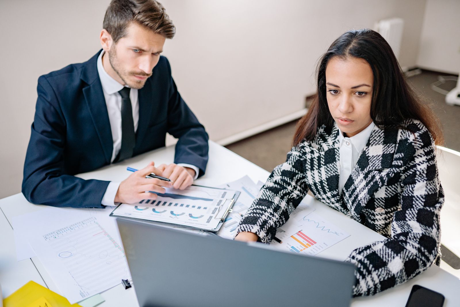 Two founders comparing financing options on a laptop with financial charts in an office