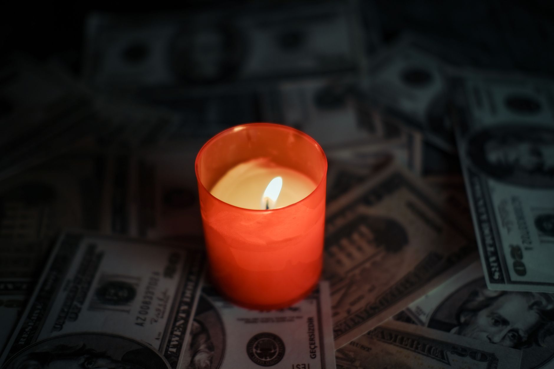 A candle burning over scattered banknotes, a picture of the cash a startup burns each month