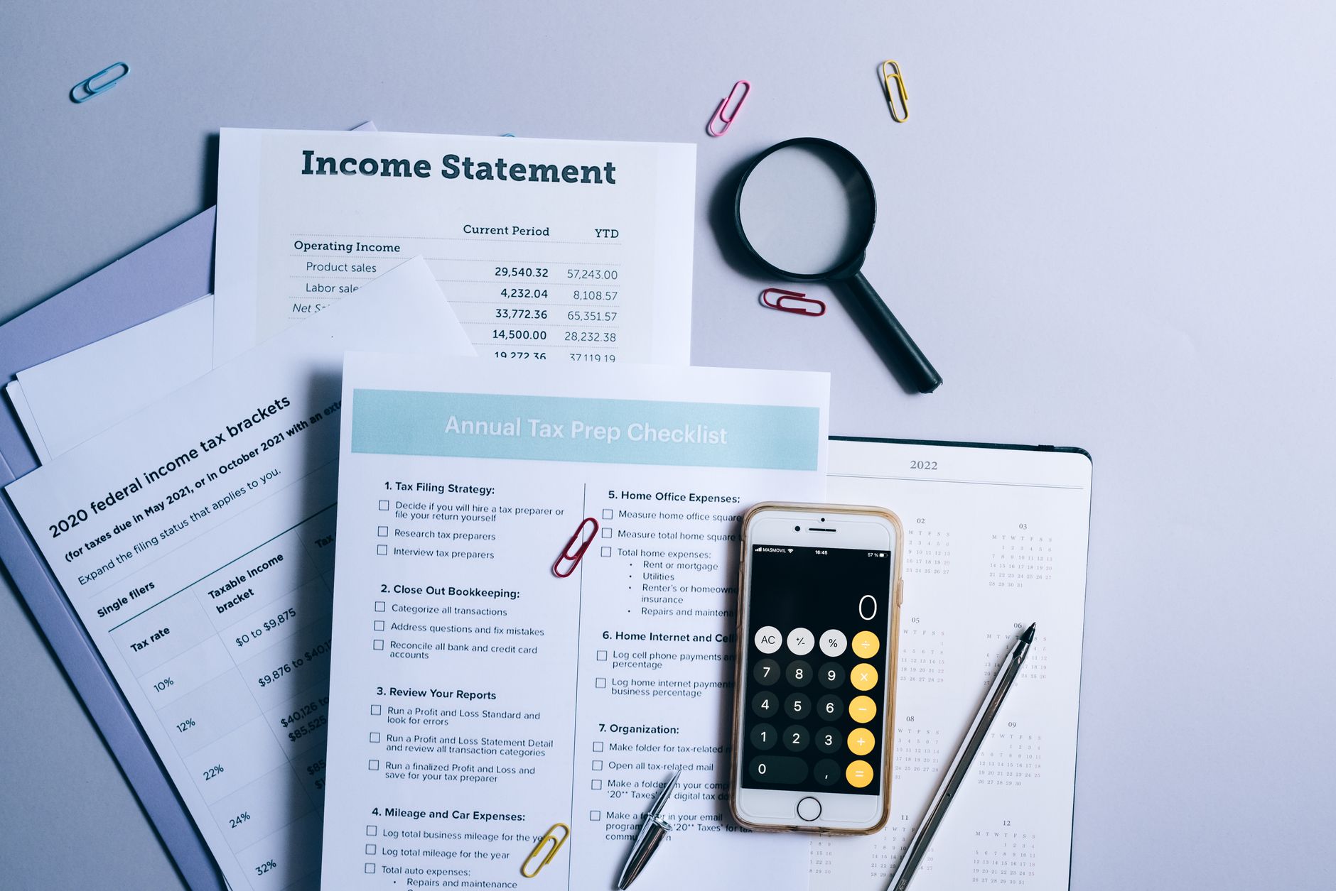Tax preparation checklist with calculator, income statement and tax forms on a desk